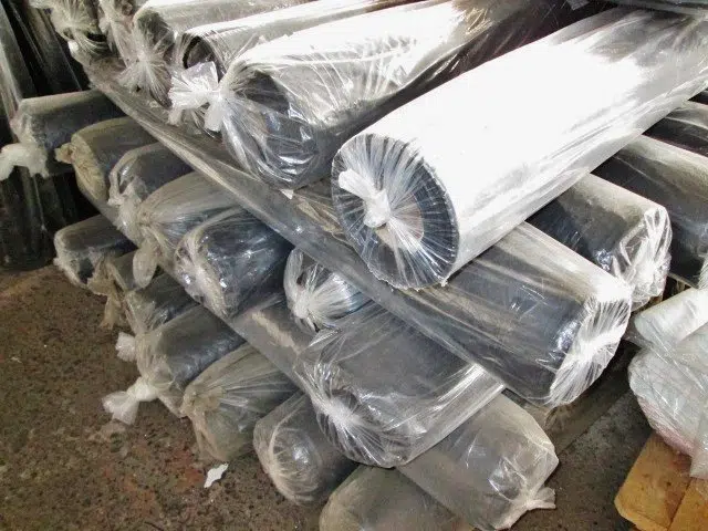 Welpac packaging company A pile of black plastic sheets stacked in a Welpac packaging company warehouse.