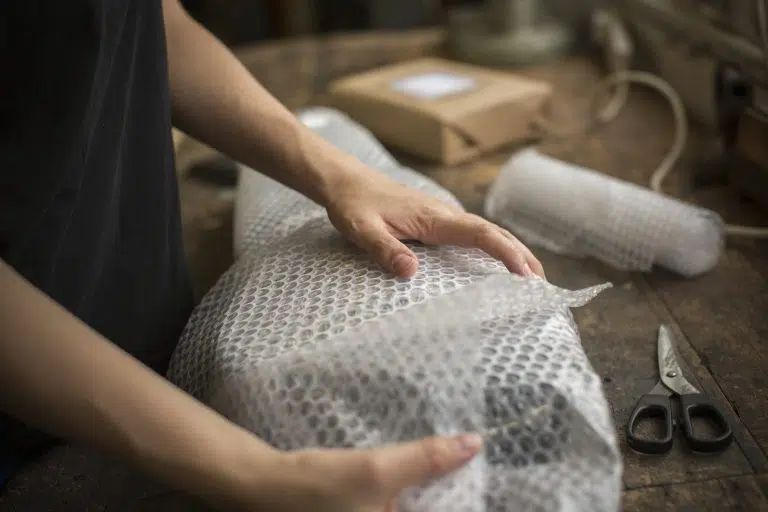 Welpac packaging company A woman is wrapping a package with bubble wrap.
