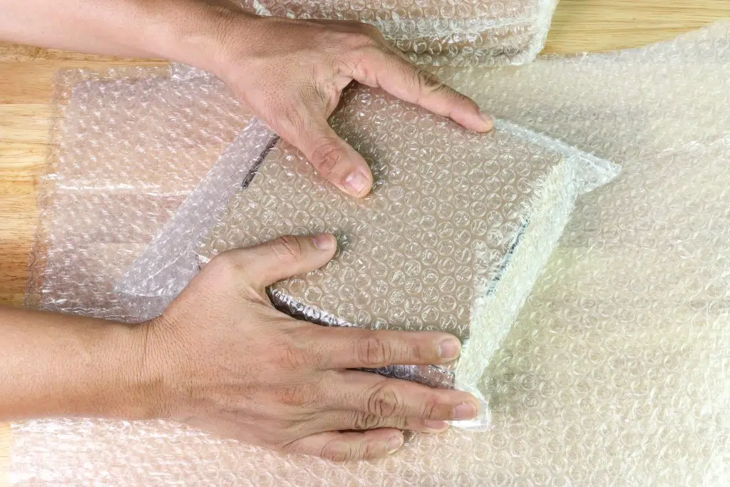 Welpac packaging company A person carefully arranging bubble wrap on top of a wooden table.