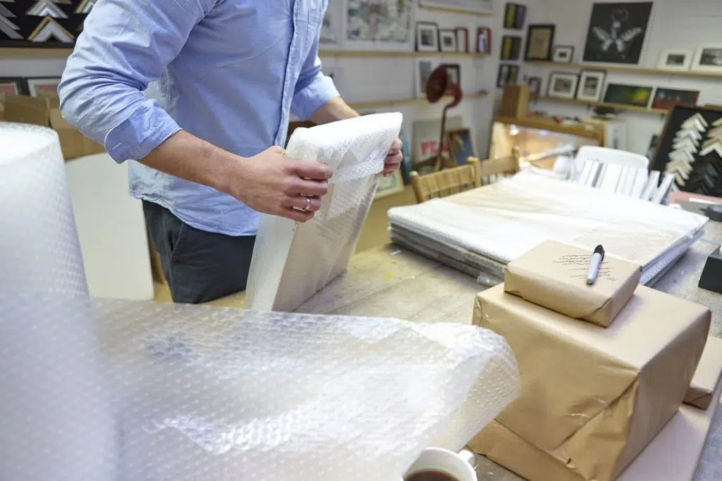 Welpac packaging company A man is meticulously wrapping a package in a studio using bubble wrap to ensure maximum protection.