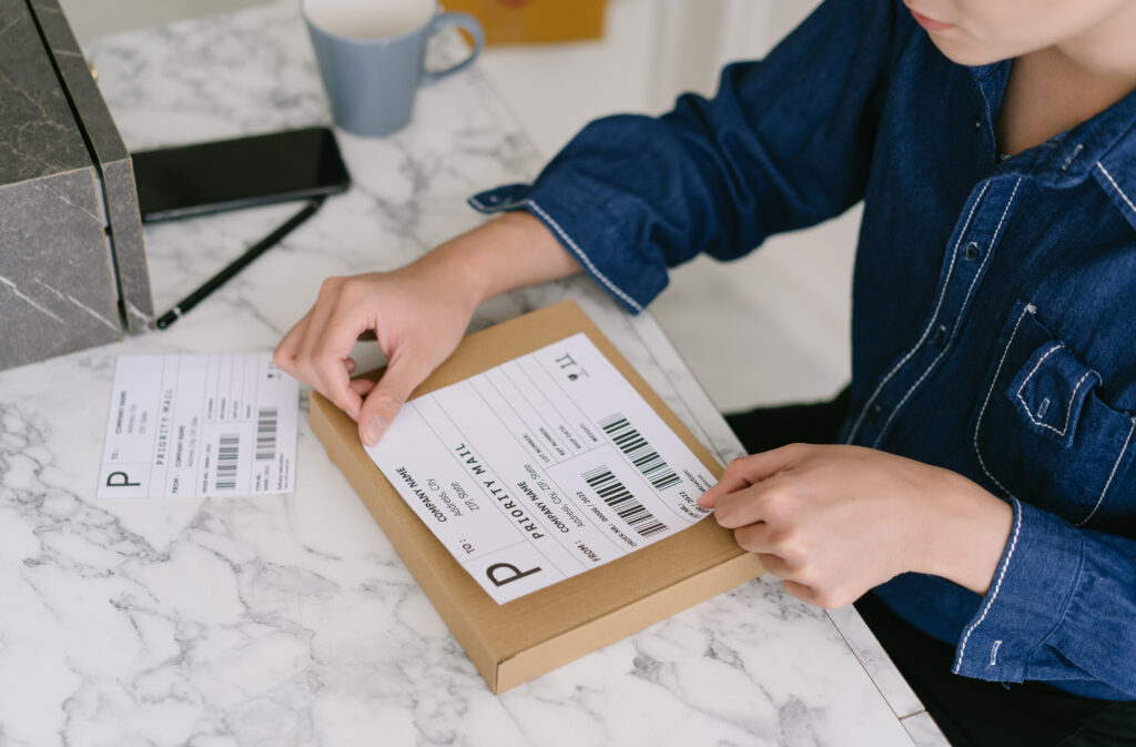 Welpac packaging company A woman is carefully affixing a shipping label on a box, emphasizing the importance of proper labeling.