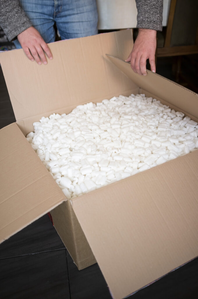 Welpac packaging company A man opening a box of white pebbles, brought to you by a company specializing in fragile item packaging solutions.